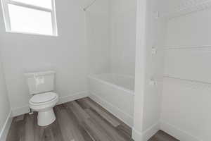 Bathroom with toilet, bathtub / shower combination, and wood-type flooring