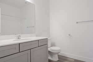 Bathroom featuring vanity, toilet, a shower, and hardwood / wood-style floors