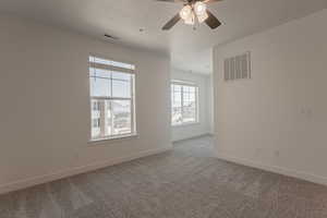 Unfurnished room with ceiling fan, carpet flooring, and a textured ceiling