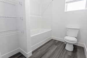 Bathroom with hardwood / wood-style floors, shower with separate bathtub, and toilet