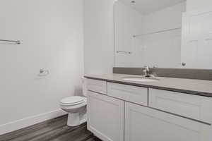 Bathroom featuring vanity, a shower, hardwood / wood-style flooring, and toilet