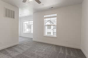 Spare room with a textured ceiling, carpet, and a wealth of natural light