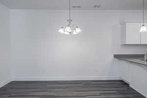 Unfurnished dining area with a notable chandelier and dark hardwood / wood-style flooring