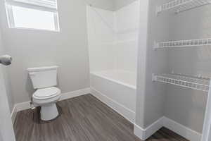 Bathroom with toilet, hardwood / wood-style floors, and washtub / shower combination