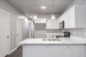 Kitchen with white cabinets, stainless steel appliances, hanging light fixtures, and sink