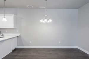 Kitchen with white cabinetry, dark hardwood / wood-style flooring, pendant lighting, and sink