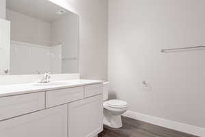 Bathroom with toilet, a shower, vanity, and wood-type flooring