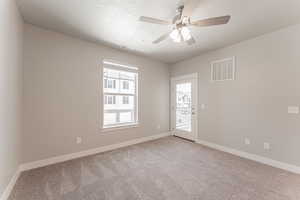 Carpeted empty room with ceiling fan and a textured ceiling