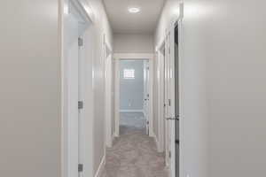 Hallway featuring light colored carpet