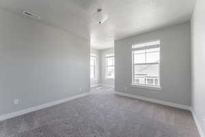 Empty room with a textured ceiling and carpet flooring