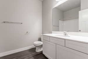 Bathroom with vanity, toilet, hardwood / wood-style flooring, and walk in shower