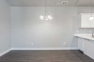 Unfurnished dining area with dark hardwood / wood-style floors and an inviting chandelier