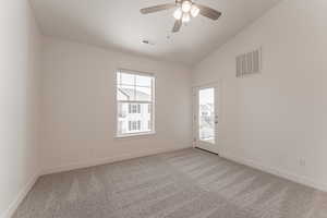 Empty room featuring ceiling fan, carpet, and vaulted ceiling