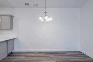 Unfurnished dining area featuring an inviting chandelier and dark hardwood / wood-style floors