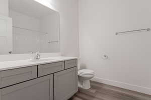 Bathroom featuring toilet, walk in shower, hardwood / wood-style flooring, and vanity