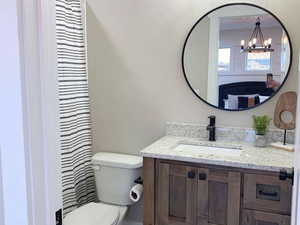 Bathroom featuring vanity, toilet, and a chandelier