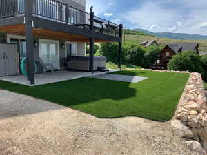 View of yard with french doors, a hot tub, a patio area, and a deck with mountain view