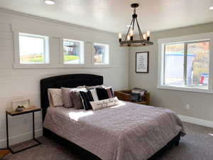 Bedroom featuring a textured ceiling, a chandelier, and multiple windows