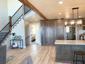 Kitchen with light hardwood / wood-style flooring, hanging light fixtures, a kitchen bar, and light stone countertops