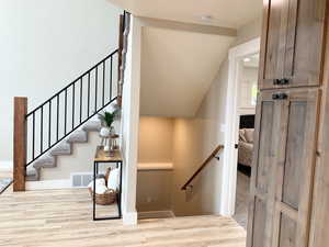 Staircase with lofted ceiling and light hardwood / wood-style floors