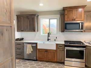 Kitchen with sink, stainless steel appliances, light stone countertops, and tasteful backsplash