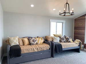 Living room featuring vaulted ceiling, carpet, a chandelier, and wooden walls