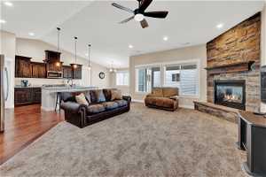 Family room with lofted ceiling, ceiling fan, carpet flooring, and a fireplace
