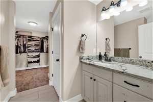 Primary bathroom with vanity with extensive cabinet space and tile floors