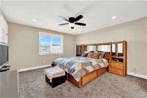 Primary carpeted bedroom featuring ceiling fan