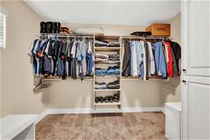 Primary walk in closet with light colored carpet