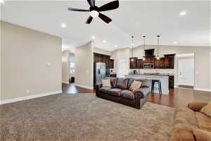 Carpeted family room with lofted ceiling, sink, and ceiling fan