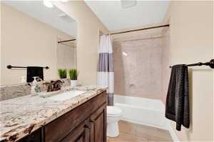 Full bathroom with shower / bathtub combination with curtain, toilet, vanity with extensive cabinet space, and tile flooring