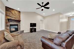 Family room featuring lofted ceiling, ceiling fan, carpet, and a stone fireplace