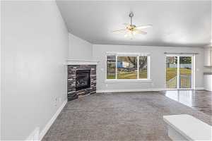 Unfurnished living room featuring light carpet, plenty of natural light, ceiling fan, and a fireplace