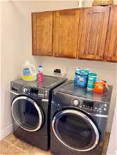 Washroom with cabinets, light tile flooring, and washing machine and clothes dryer