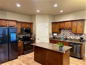Kitchen featuring appliances with stainless steel finishes, tasteful backsplash, and light hardwood / wood-style flooring