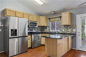 Kitchen with appliances with stainless steel finishes, tasteful backsplash, and wood-type flooring