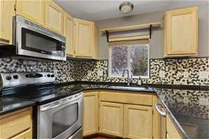 Kitchen featuring tasteful backsplash, appliances with stainless steel finishes, light brown cabinets, and sink
