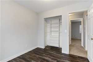 Unfurnished bedroom featuring a closet and dark hardwood / wood-style floors