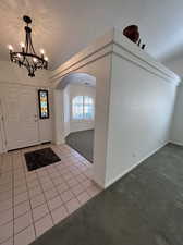 Foyer entrance featuring a notable chandelier and light tile floor