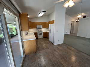 Kitchen featuring ceiling fan, double sink, white appliances, and vaulted ceiling