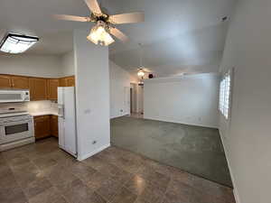 Kitchen with vaulted ceiling, white appliances, and ceiling fan