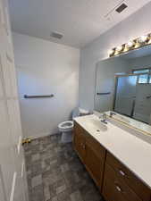 Bathroom featuring vanity, toilet, and a shower with door