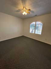 Carpeted spare room featuring a textured ceiling and ceiling fan