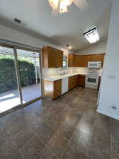 Kitchen with white appliances, lofted ceiling, ceiling fan, and double sink