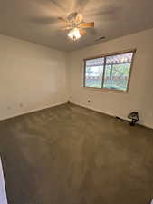 Carpeted empty room featuring ceiling fan and natural light