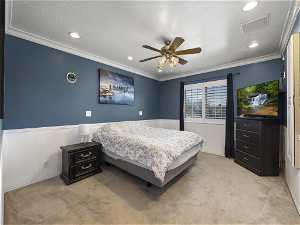 Bedroom featuring ornamental molding, light colored carpet, ceiling fan, and a textured ceiling