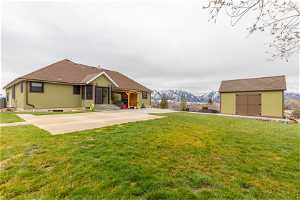 Back of property with a patio, a storage shed, a yard, and a mountain view