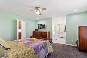Carpeted bedroom with ensuite bathroom, sink, and ceiling fan