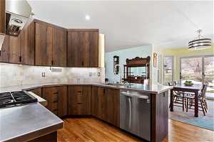 Kitchen featuring light hardwood / wood-style floors, backsplash, dishwasher, pendant lighting, and sink